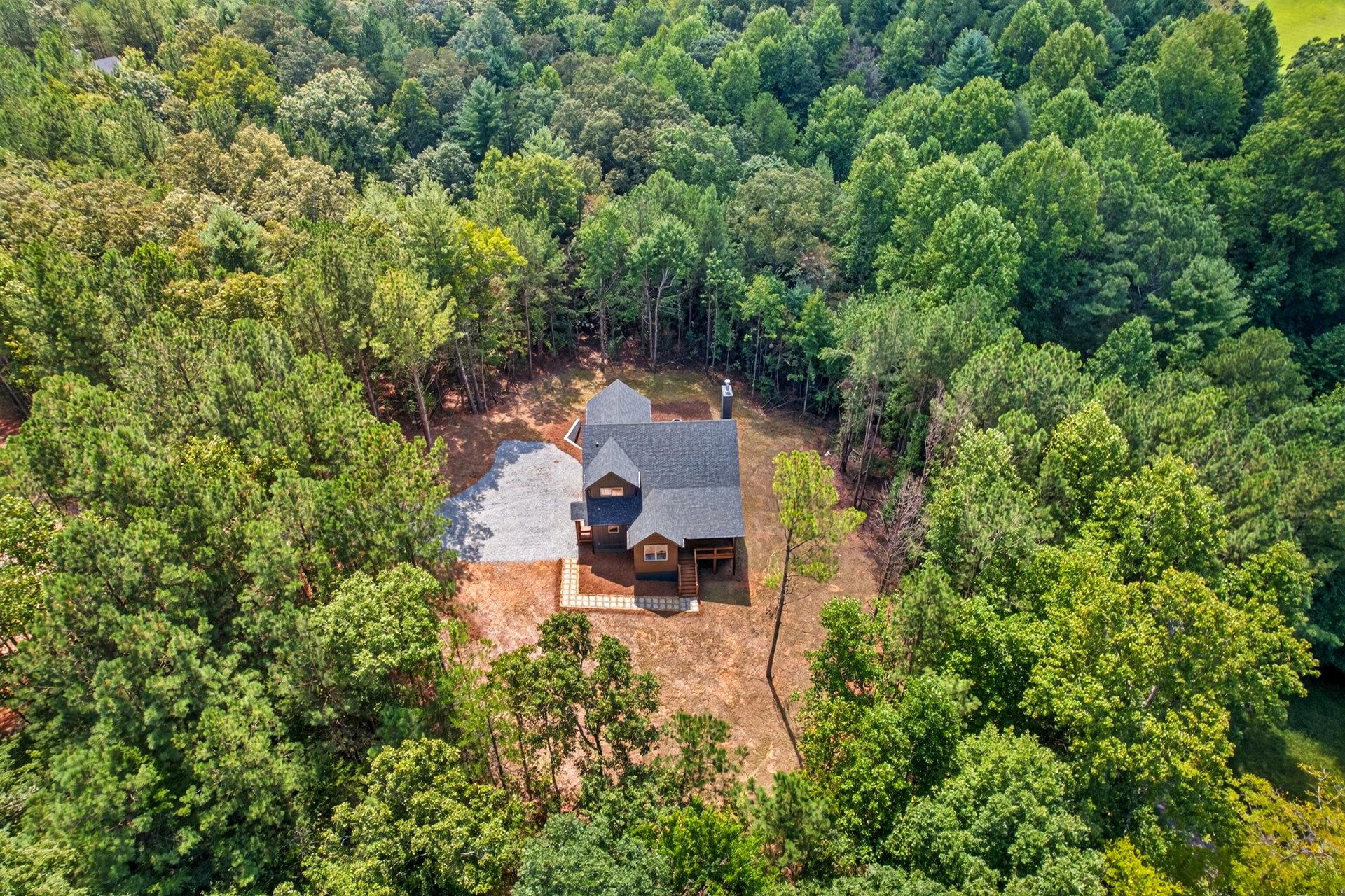 Aerial view of the dark gray home in a wooded clearing at 824 Banks Rd, Ellijay, GA