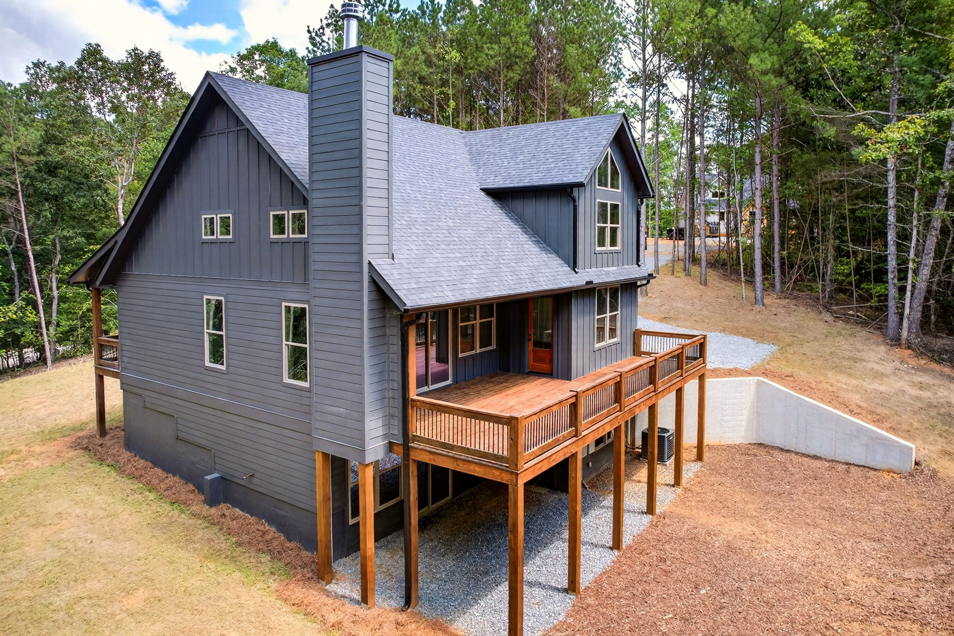 Rear corner of the home with chimney, deck, and retaining wall at 824 Banks Rd, Ellijay, GA