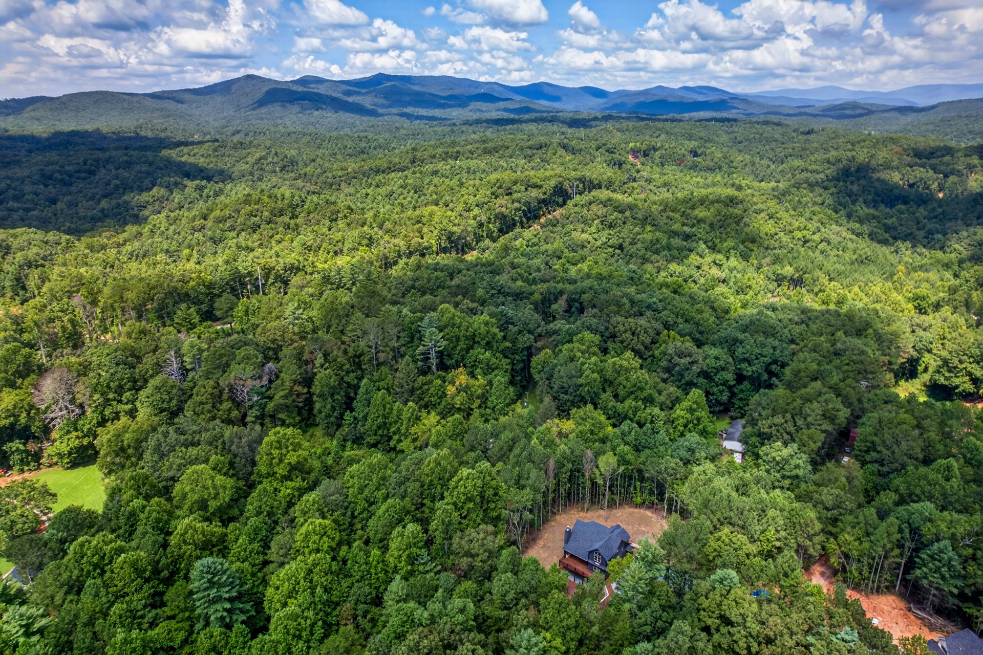 High aerial view of the home in rolling forest at 824 Banks Rd, Ellijay, GA