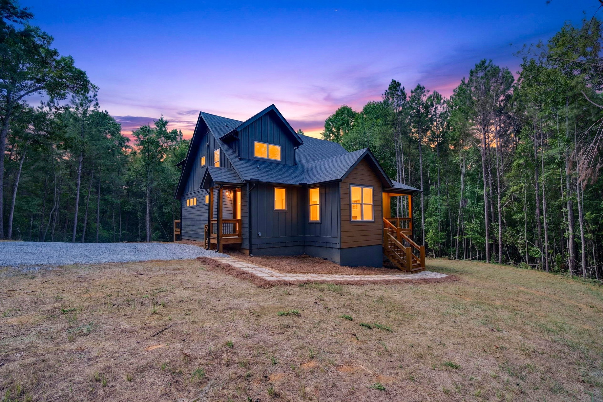 Dusk view of the back of the home with lit windows and wood deck at 824 Banks Rd, Ellijay, GA