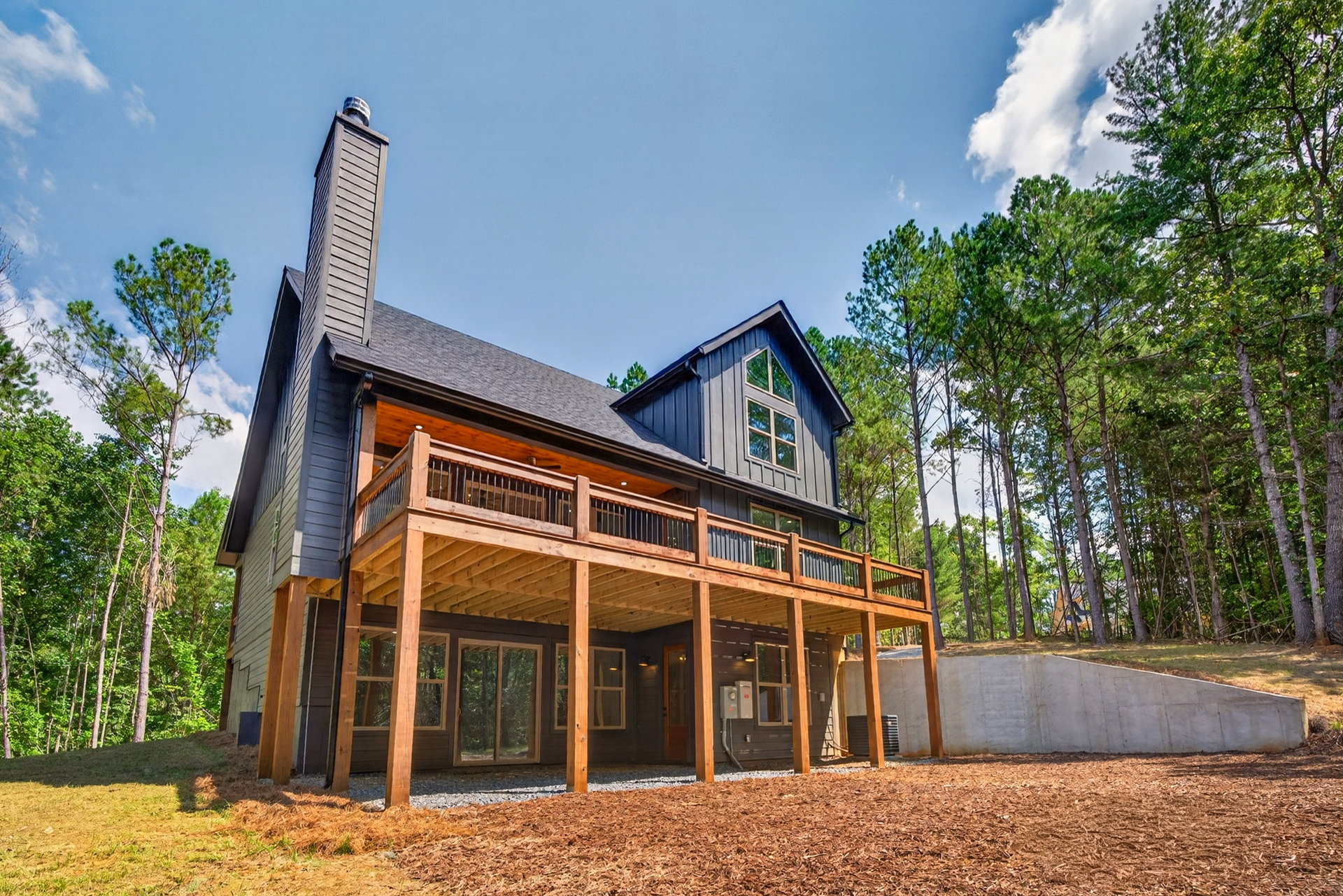 Rear exterior with dark siding, decks, and stone chimney at 824 Banks Rd, Ellijay, GA