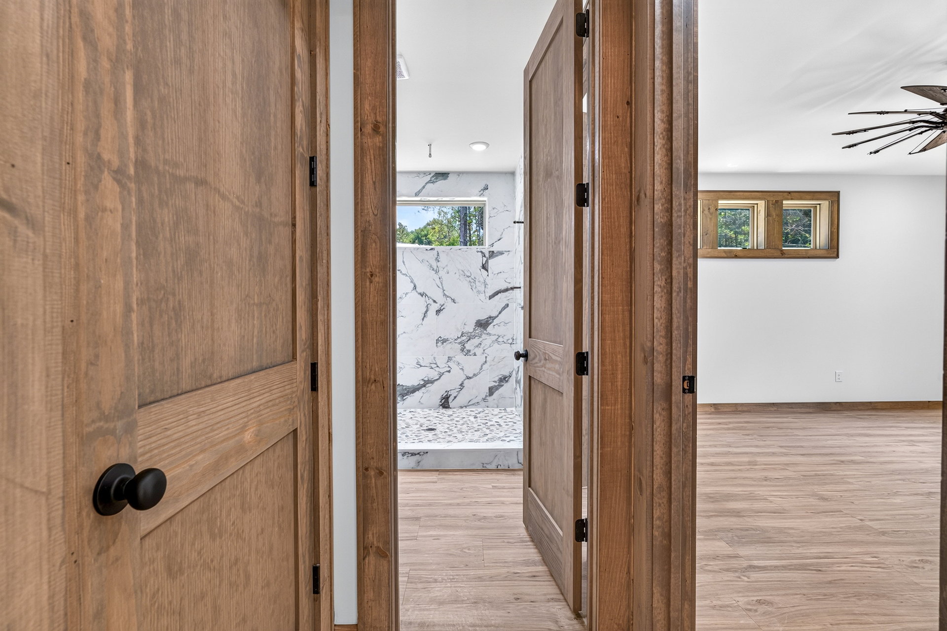 View through a wood door toward a marble-look walk-in shower at 824 Banks Rd, Ellijay, GA