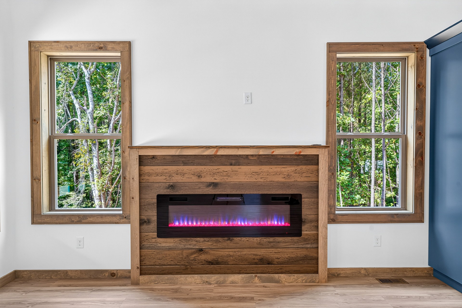 Linear fireplace with wood-plank surround between tall windows at 824 Banks Rd, Ellijay, GA