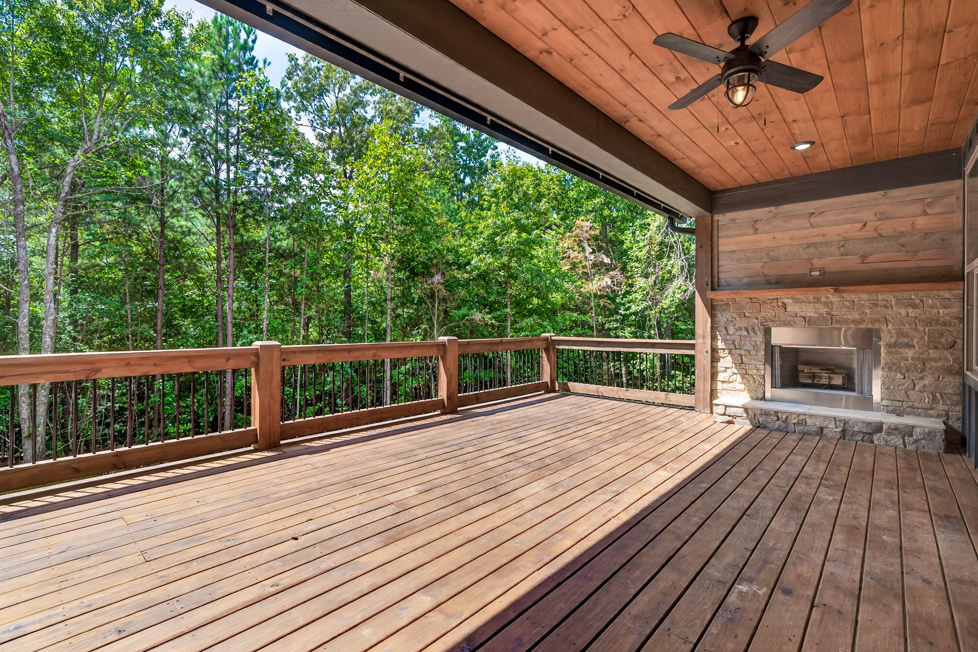 Covered wood deck with ceiling fan and stacked-stone outdoor fireplace at 824 Banks Rd, Ellijay, GA