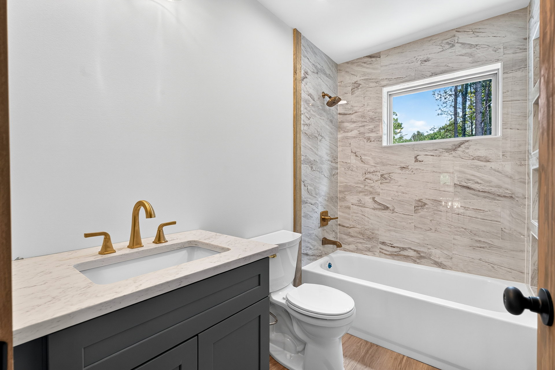 Bath with dark vanity, gold fixtures, toilet, and tiled tub at 824 Banks Rd, Ellijay, GA