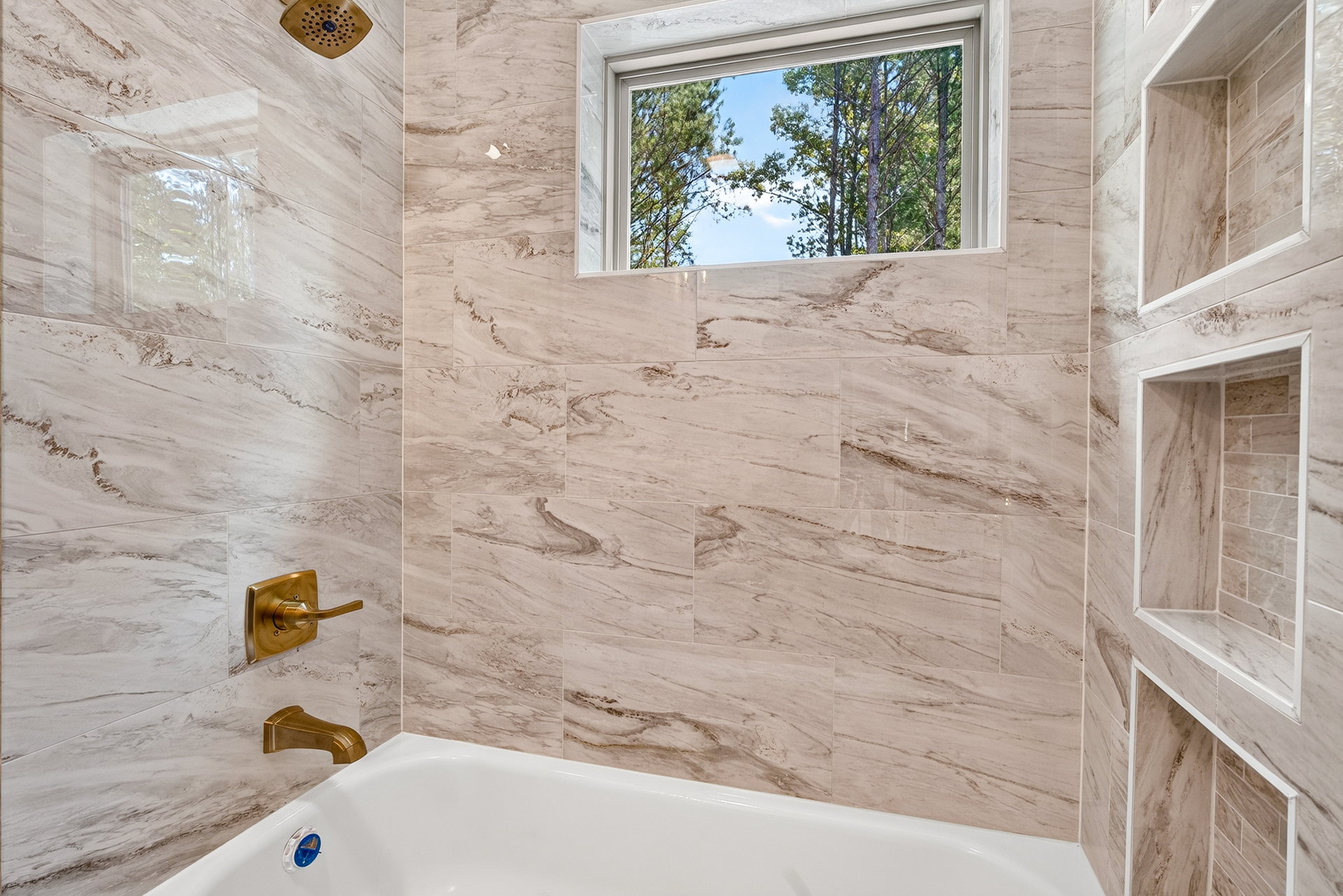 Tiled tub and shower with gold fixtures and niches at 824 Banks Rd, Ellijay, GA