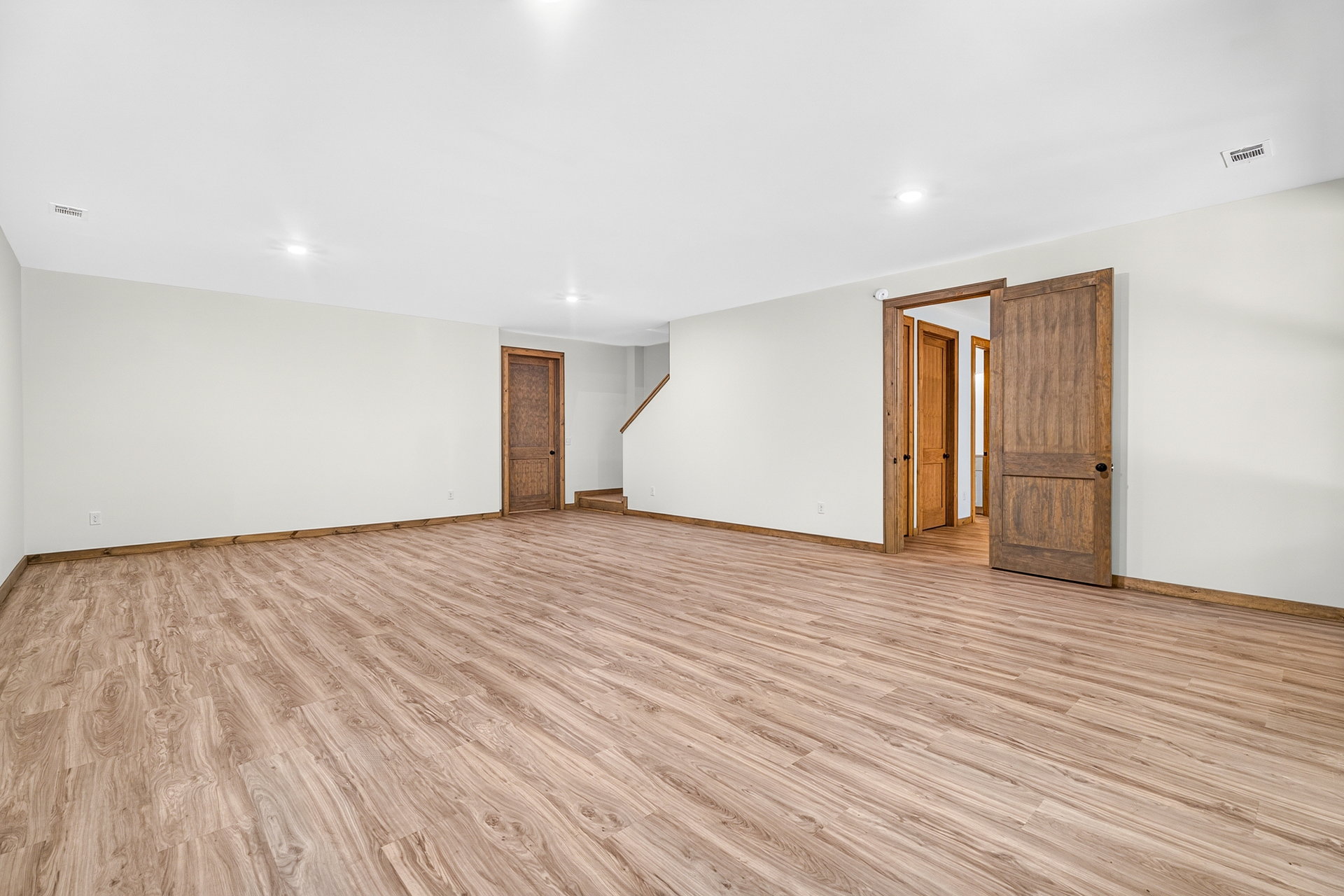 Wide view of the lower-level space with wood floors and doors at 824 Banks Rd, Ellijay, GA