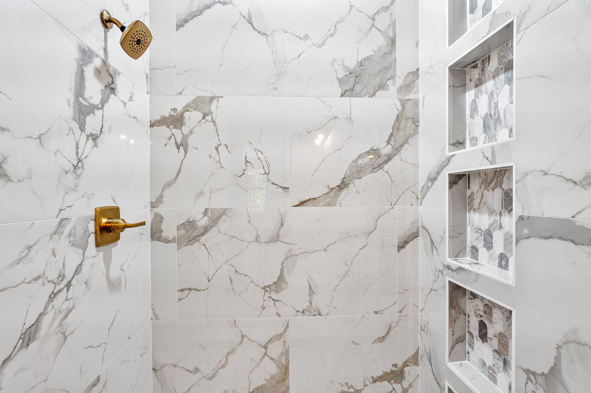 Walk-in shower with marble-look tile, gold fixtures, and tiled niche at 824 Banks Rd, Ellijay, GA