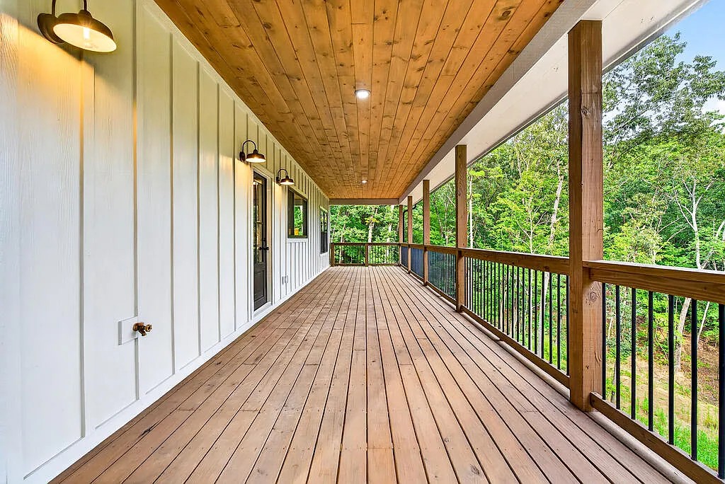 Bedroom with a woven headboard, wooded-view windows, and a ceiling fan