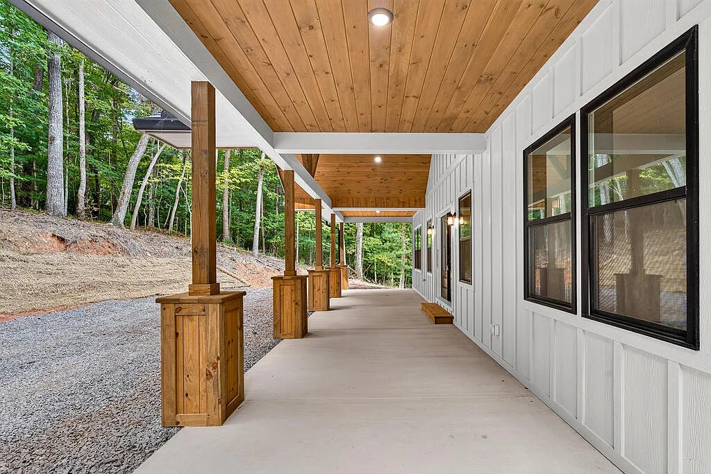 Open kitchen and living area with navy cabinets, vaulted beamed ceiling, and light wood floors