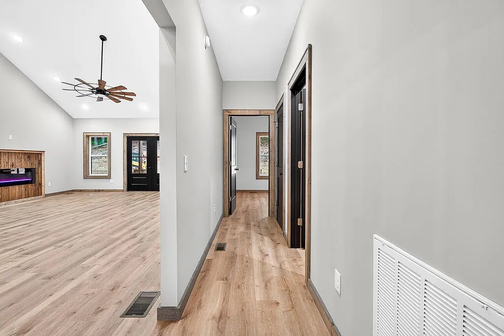Hallway looking into a living area with a wood-surround fireplace and black-trimmed doors