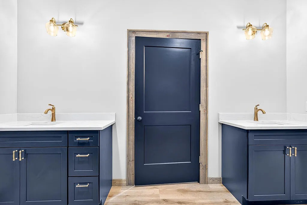 Bath with navy vanities, gold fixtures, and a navy interior door