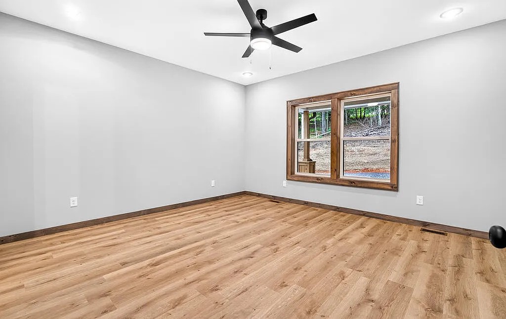 Bedroom with light wood floors, a wood-framed window, and a black ceiling fan