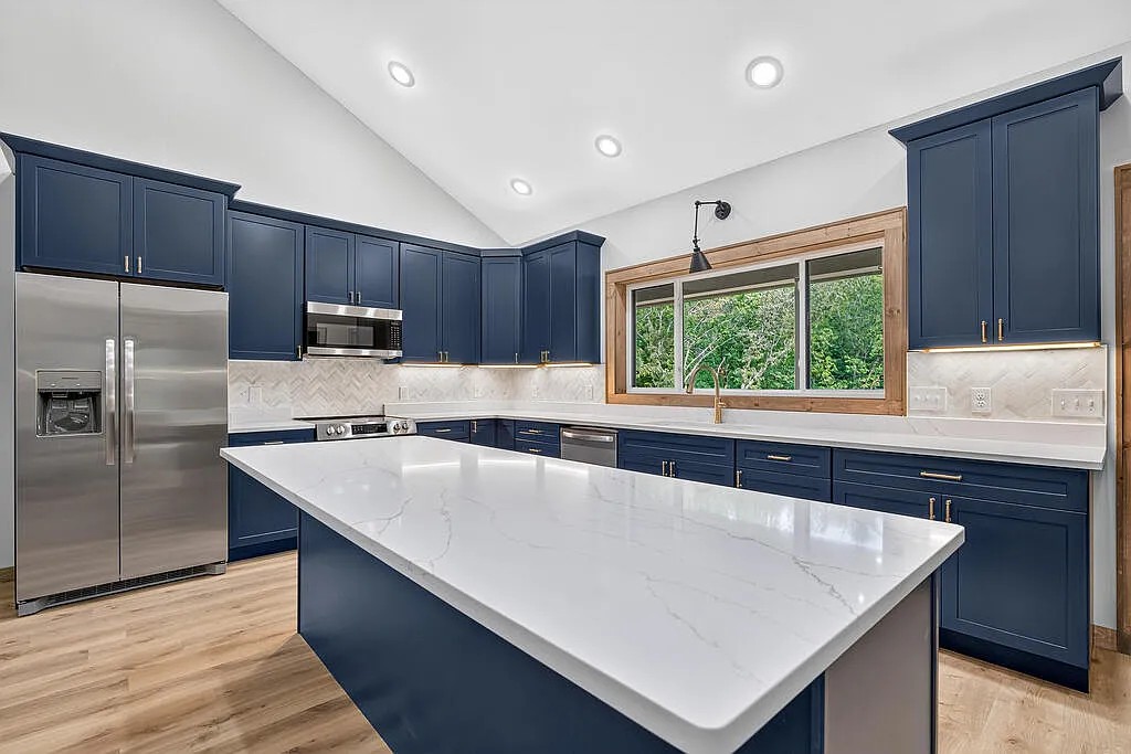 Kitchen with navy cabinets, a center island, and a wood-framed window over the sink