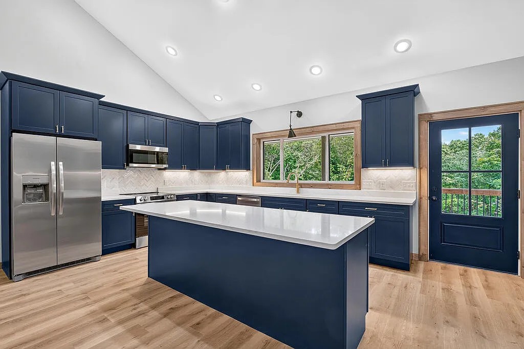 Kitchen with a navy island, stainless appliances, and a glass-pane door