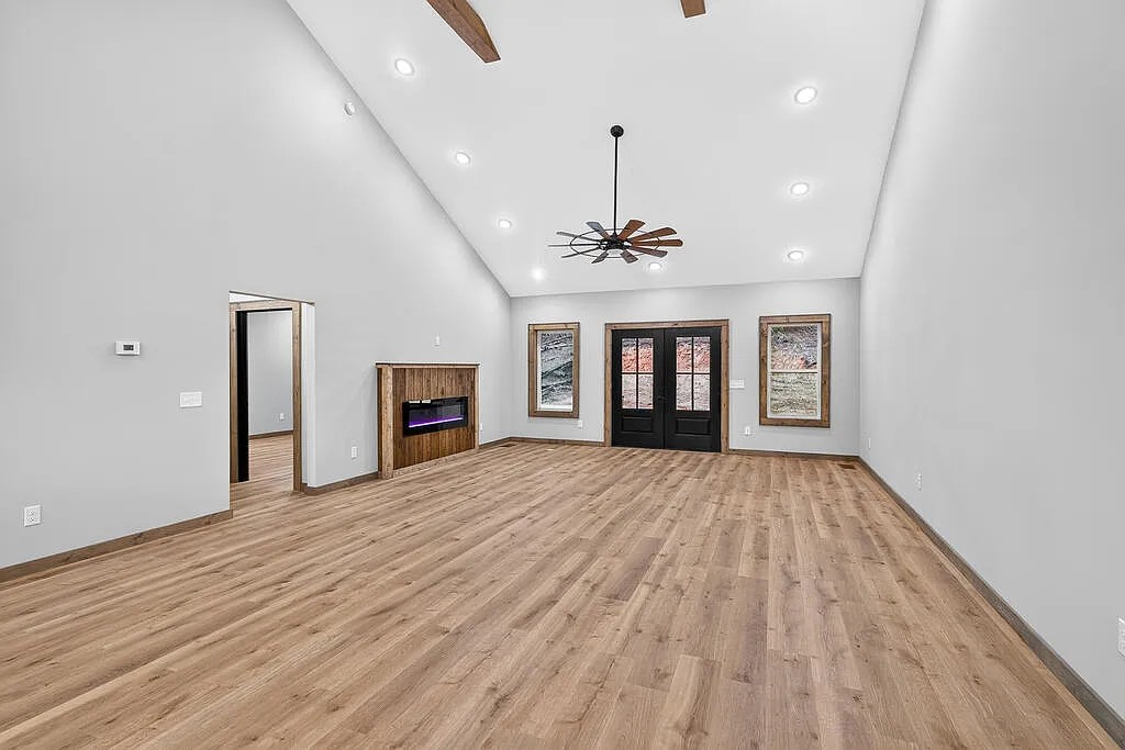 Vaulted living area with a wood-surround fireplace and glass-pane double doors