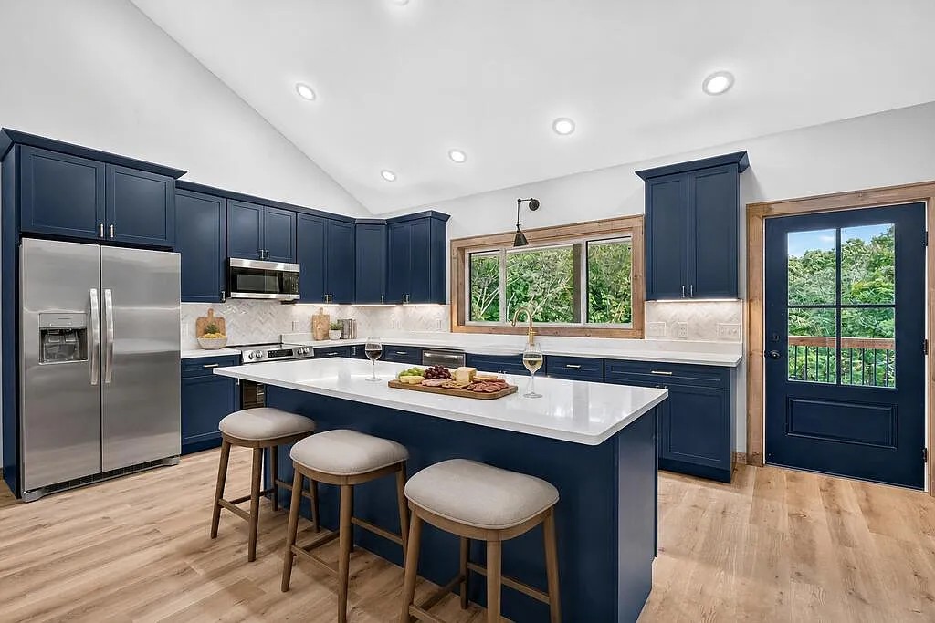 Kitchen with a navy island, bar stools, stainless appliances, and a glass-pane door