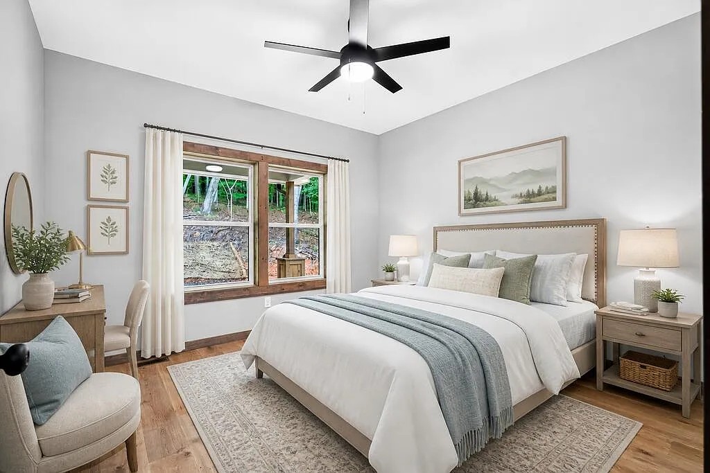 Bedroom with an upholstered headboard, wood nightstands, and a wooded-view window