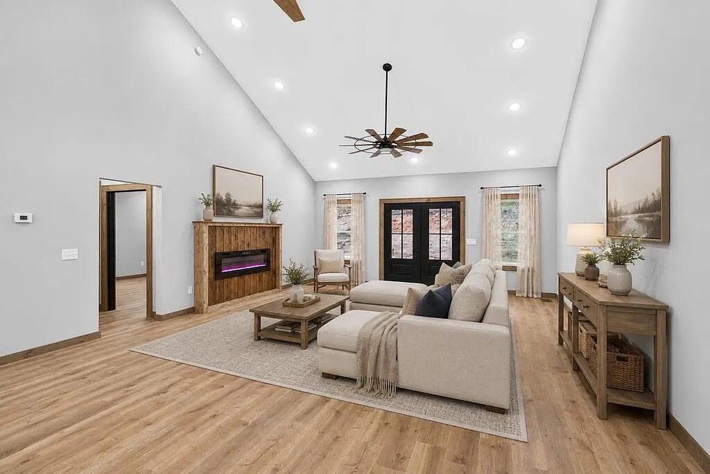 Living room with a beige sectional, wood-surround fireplace, and vaulted ceiling