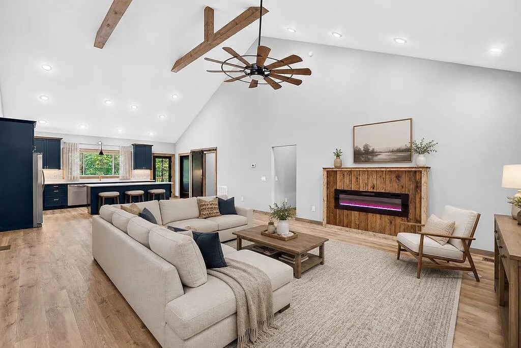 Living room with a beige sectional, wood-surround fireplace, and kitchen island beyond