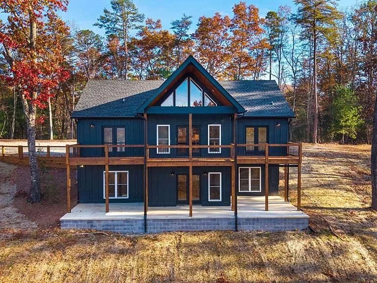 Rear of a charcoal home with two levels of wood decks and a walk-out patio