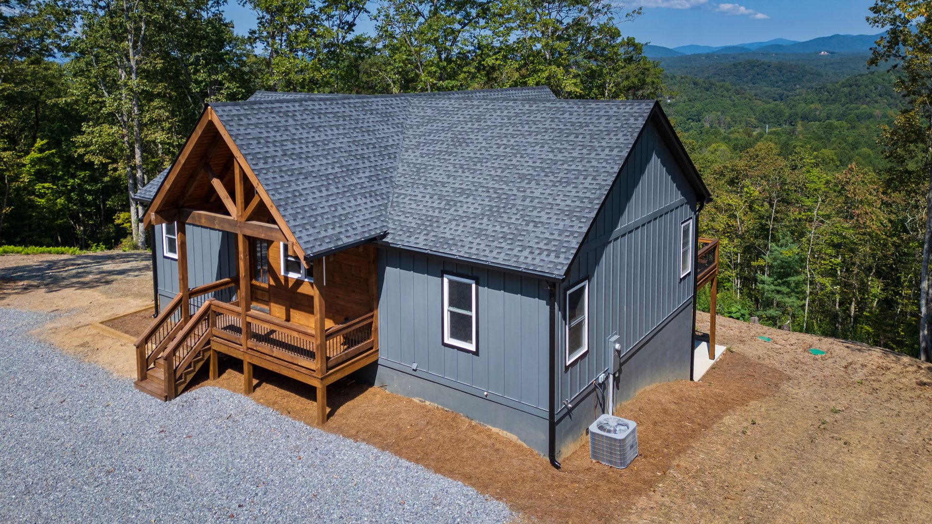 Side angle of a grey home with black-trimmed windows and a timber porch
