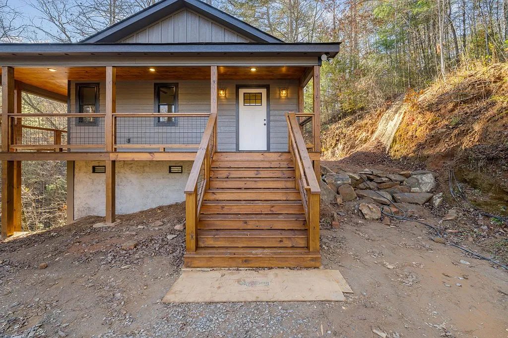 Tan-sided home with a natural wood staircase leading to a covered front porch
