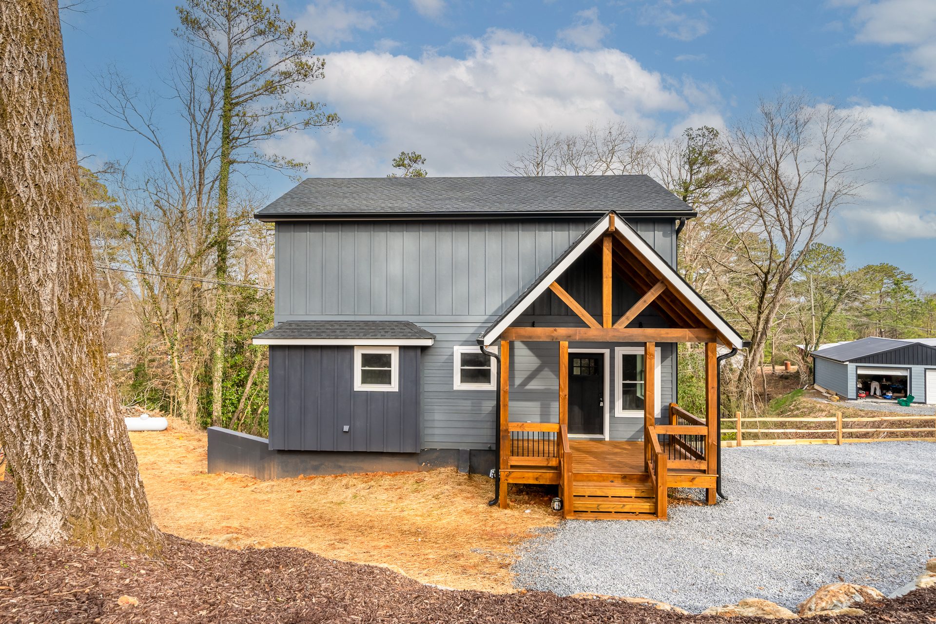Front entrance of a blue-gray home with natural wood timber porch framing