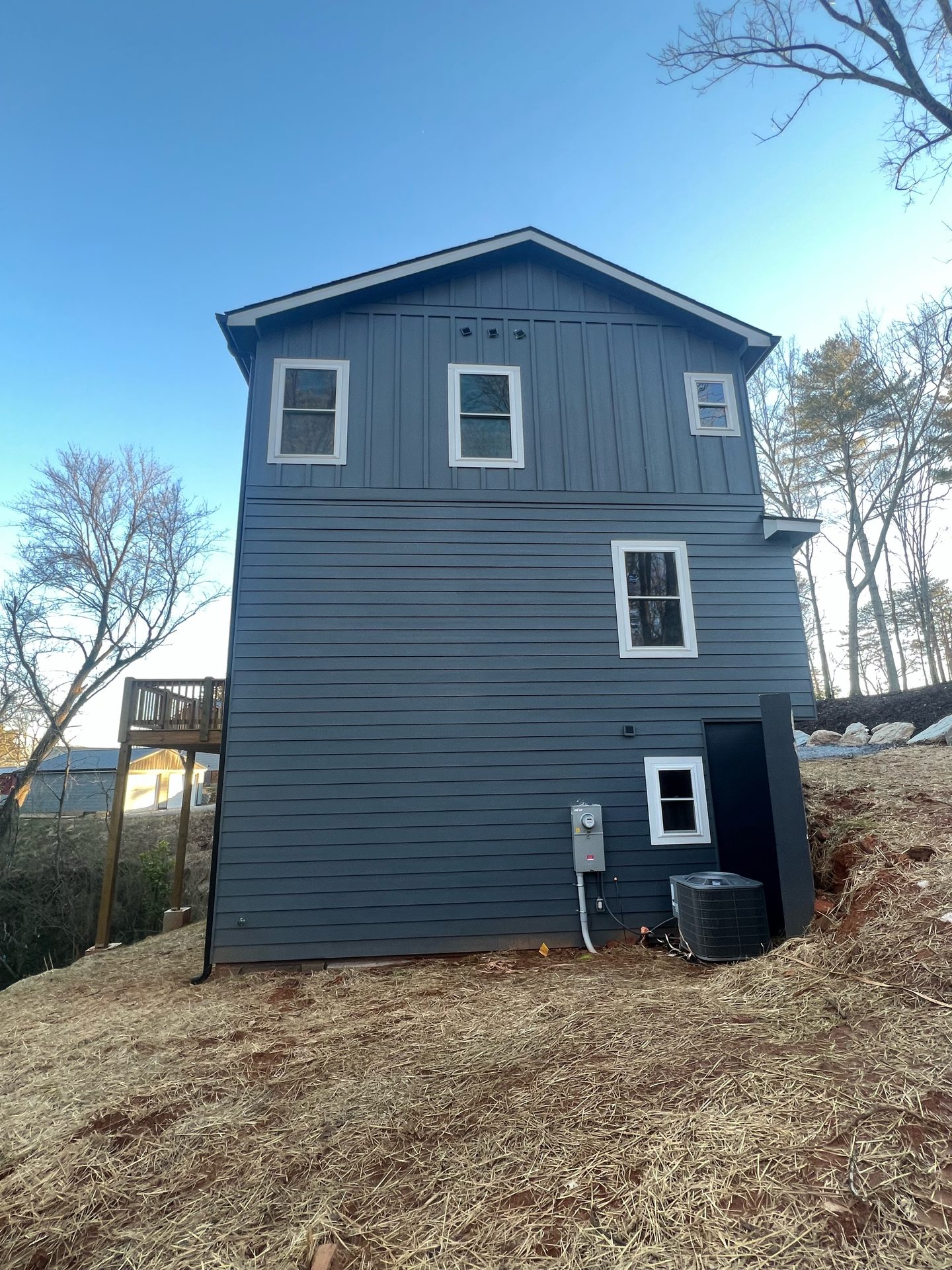 Side gable of a blue-gray home with dark siding and few windows
