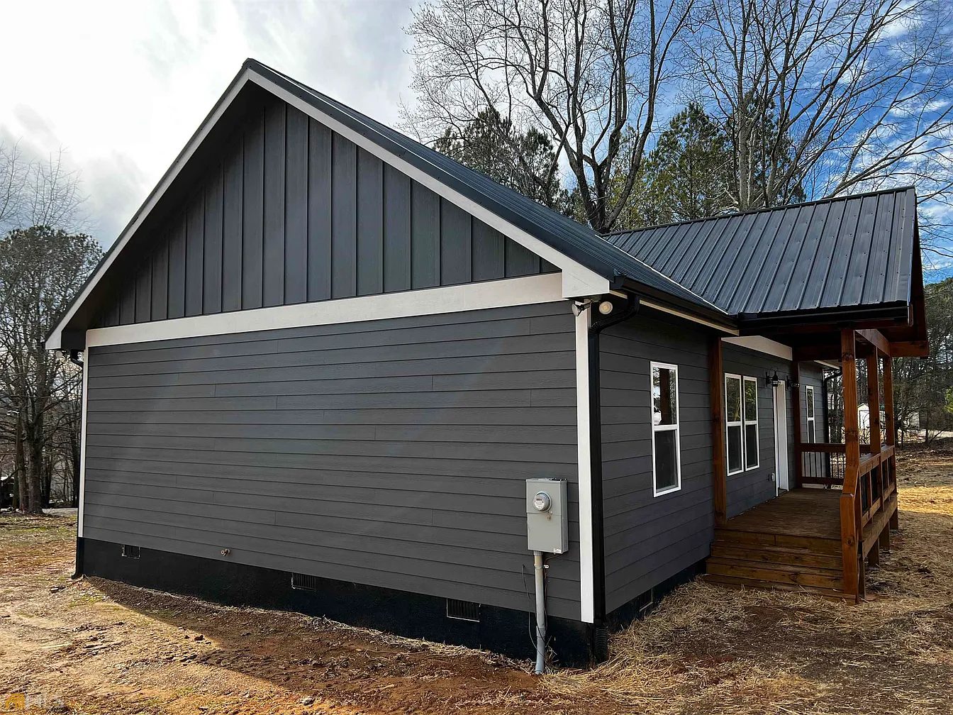 Side of a charcoal home with dark siding, white trim, and a black metal roof