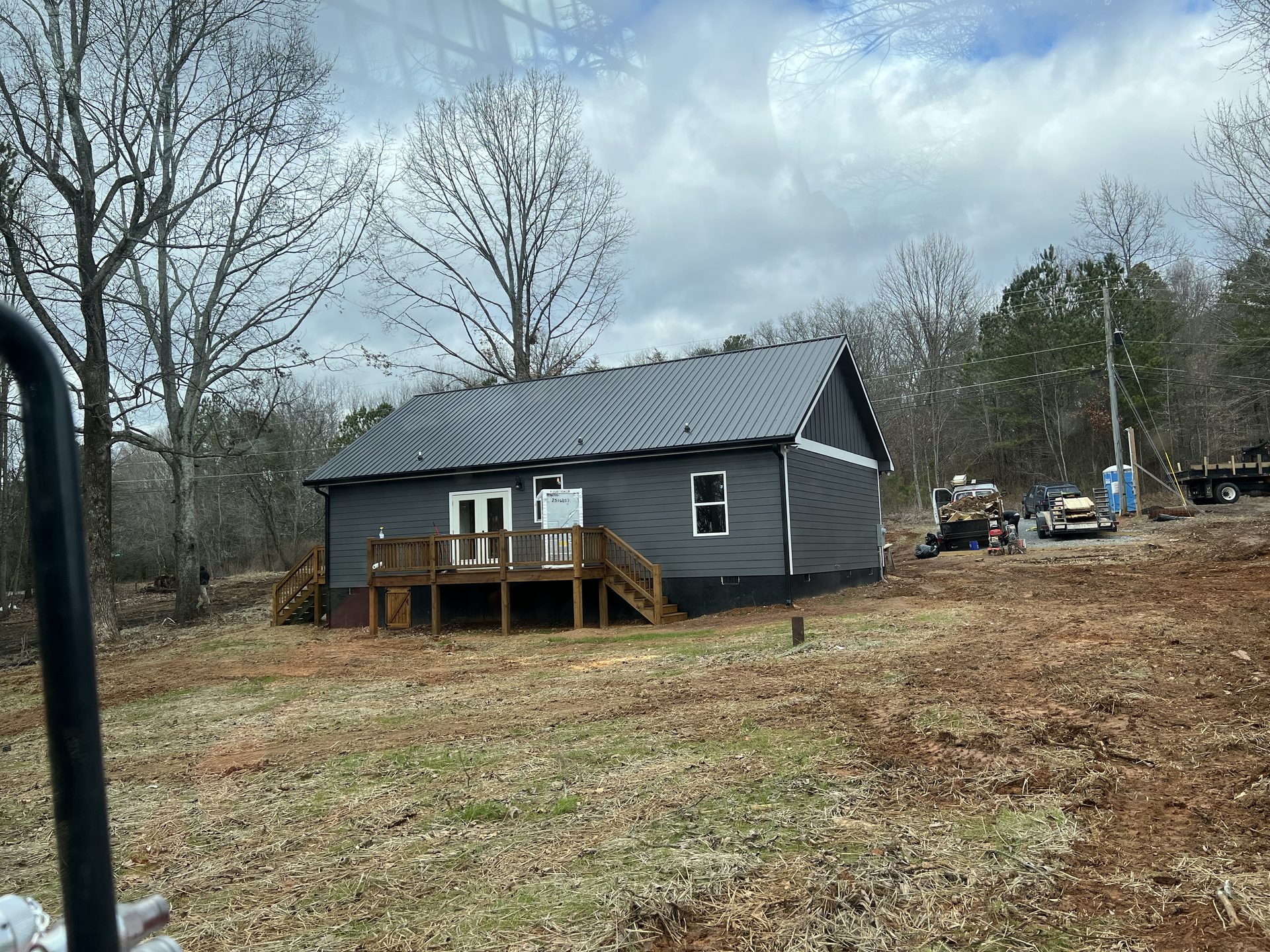Rear of a charcoal new home with a wood back deck on a cleared lot