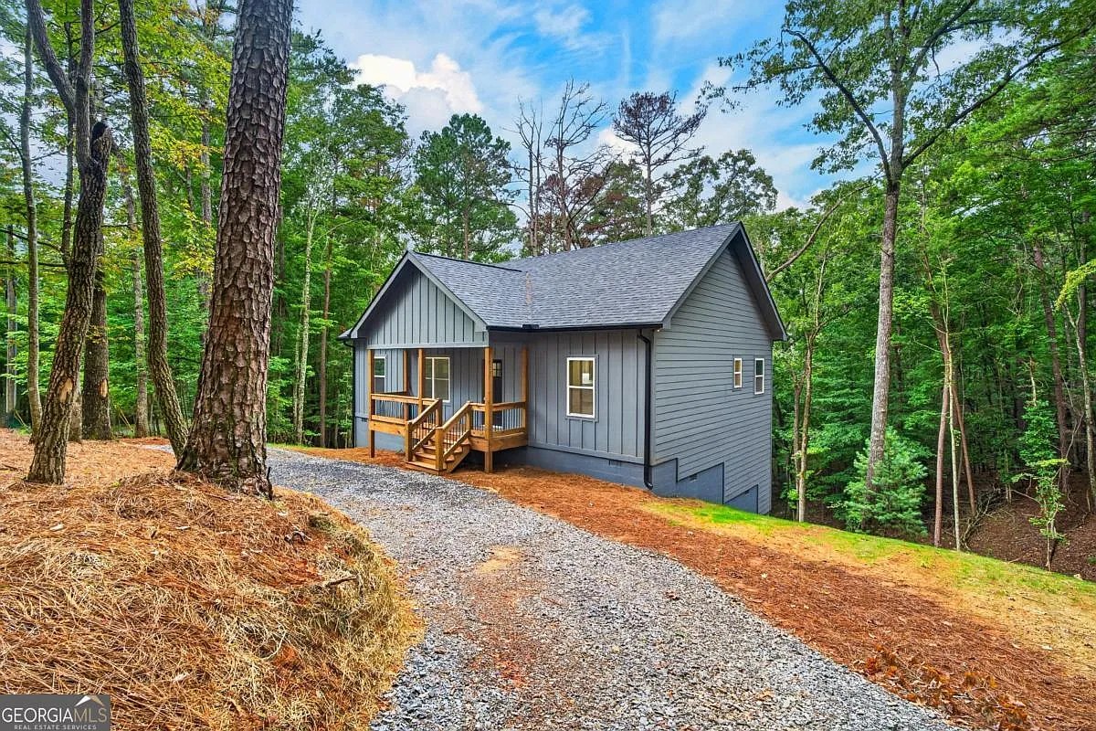 Front of the grey-blue home with gravel driveway and wood porch at 579 Julep Circle, Ellijay, GA
