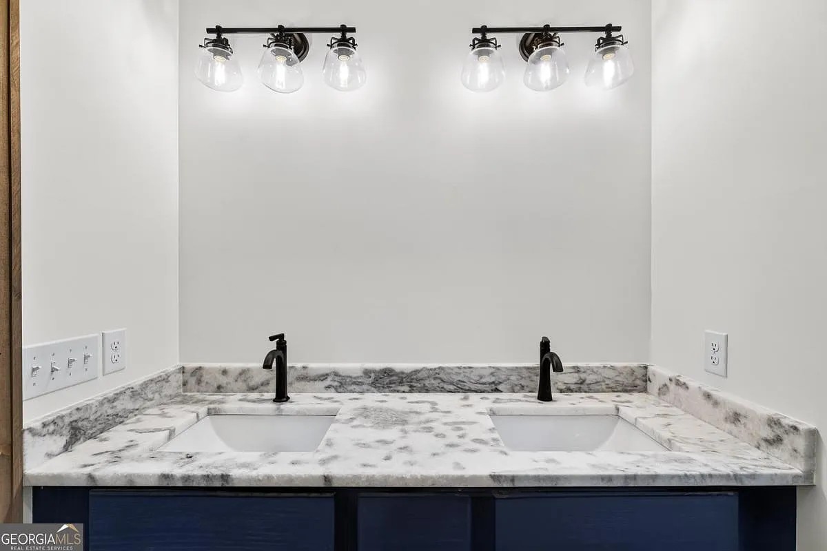 Double vanity with marble-look counters, dark cabinets, and black faucets