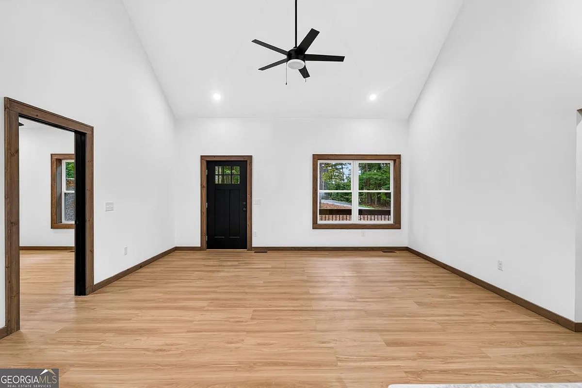 Living area with vaulted ceiling, a dark wood door, and a wooded-view window