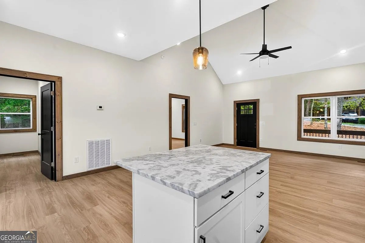 Kitchen island with marble-look counters looking toward a vaulted living area