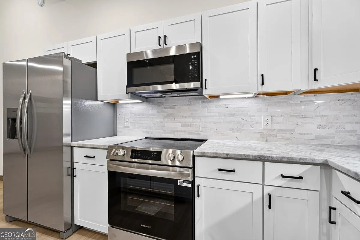 Kitchen with white shaker cabinets, marble-look counters, and stainless appliances