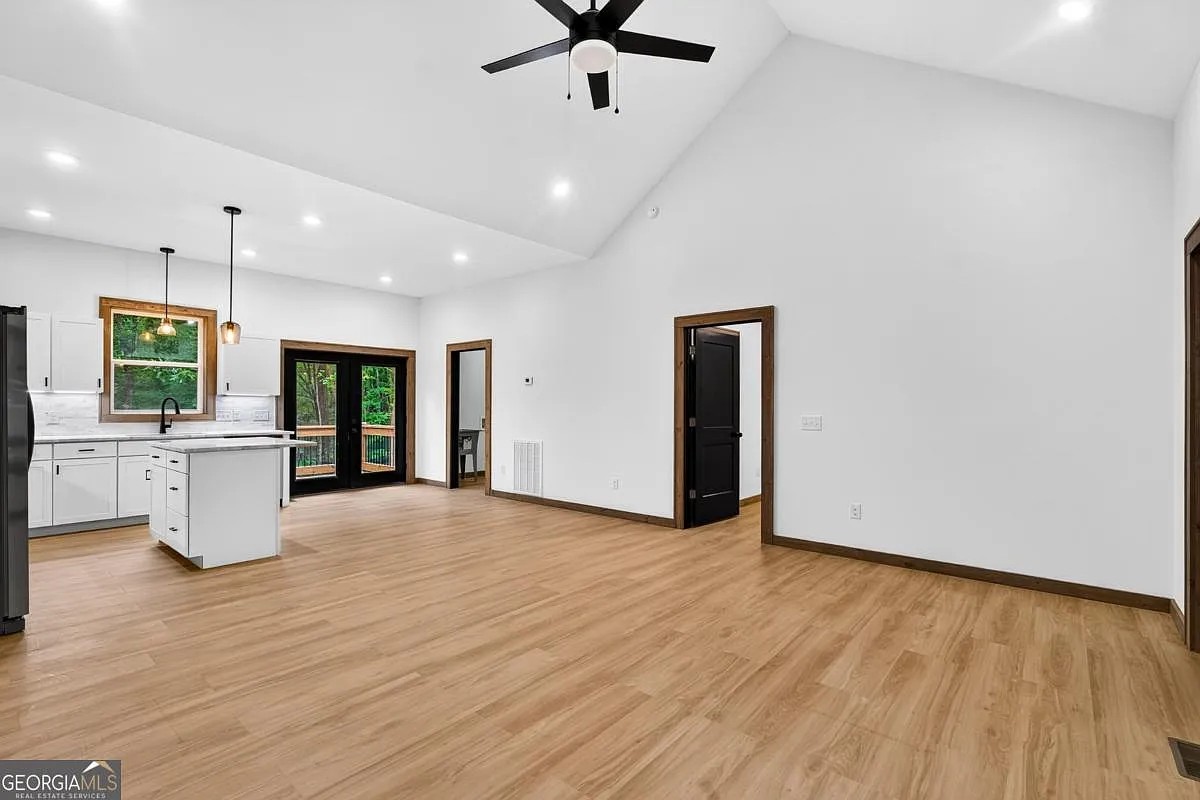 Kitchen island and living area with vaulted ceiling and glass doors to the deck