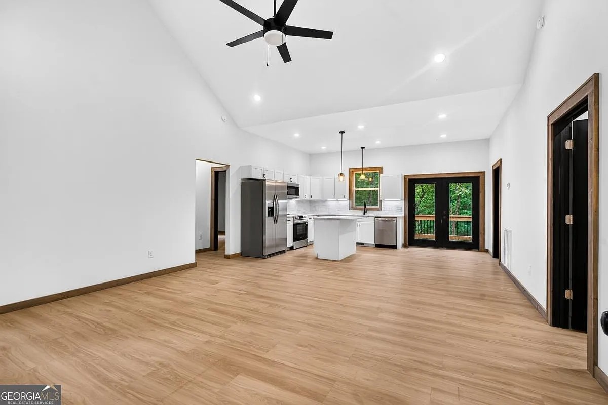 Open living area and kitchen with vaulted ceiling and glass doors to the deck