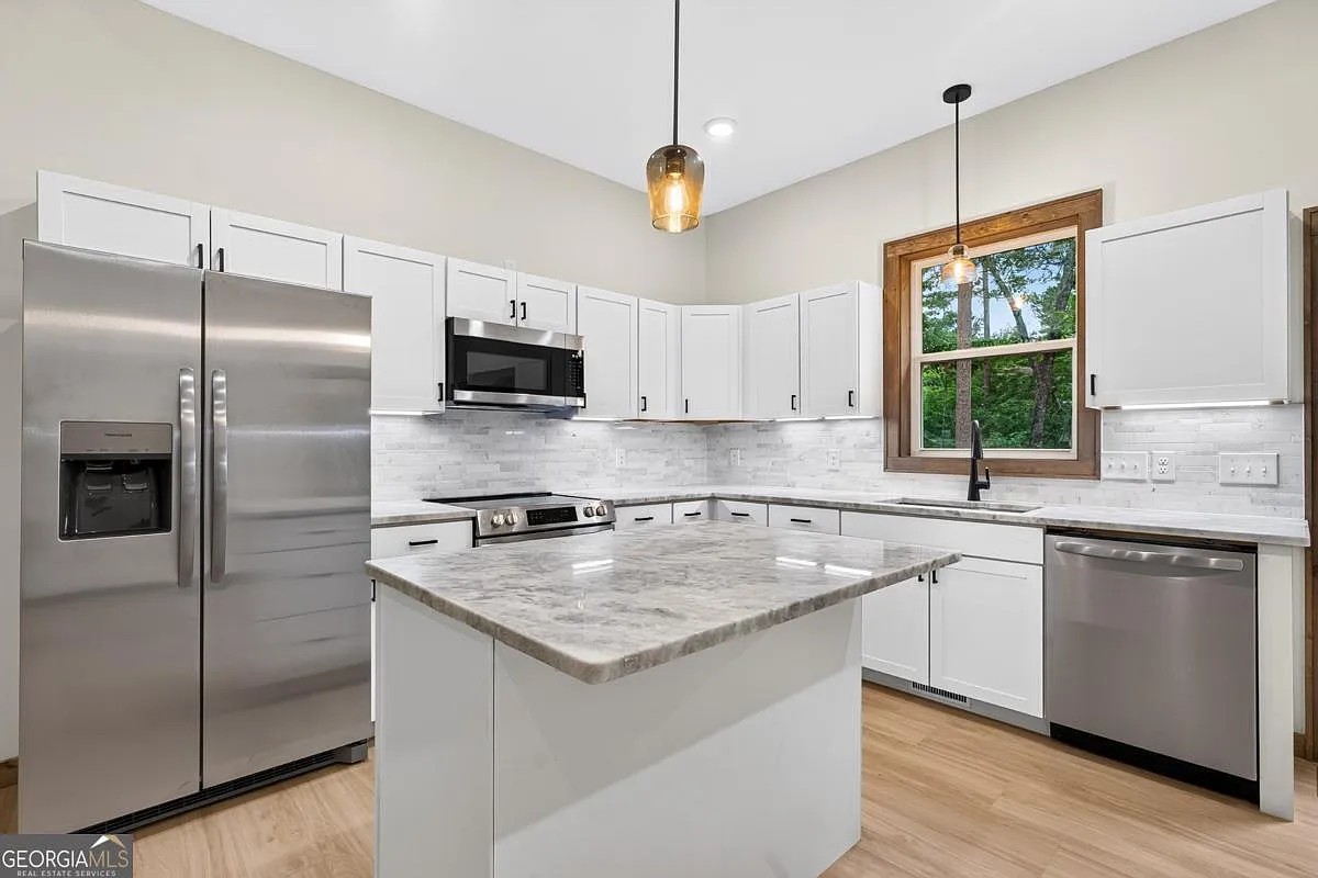 Kitchen with white cabinets, a center island, and a wood-framed window over the sink